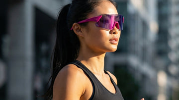 Asian female runner wearing pink 2nu performance sunglasses in bright urban light, showing low-bridge running fit and stable outdoor comfort