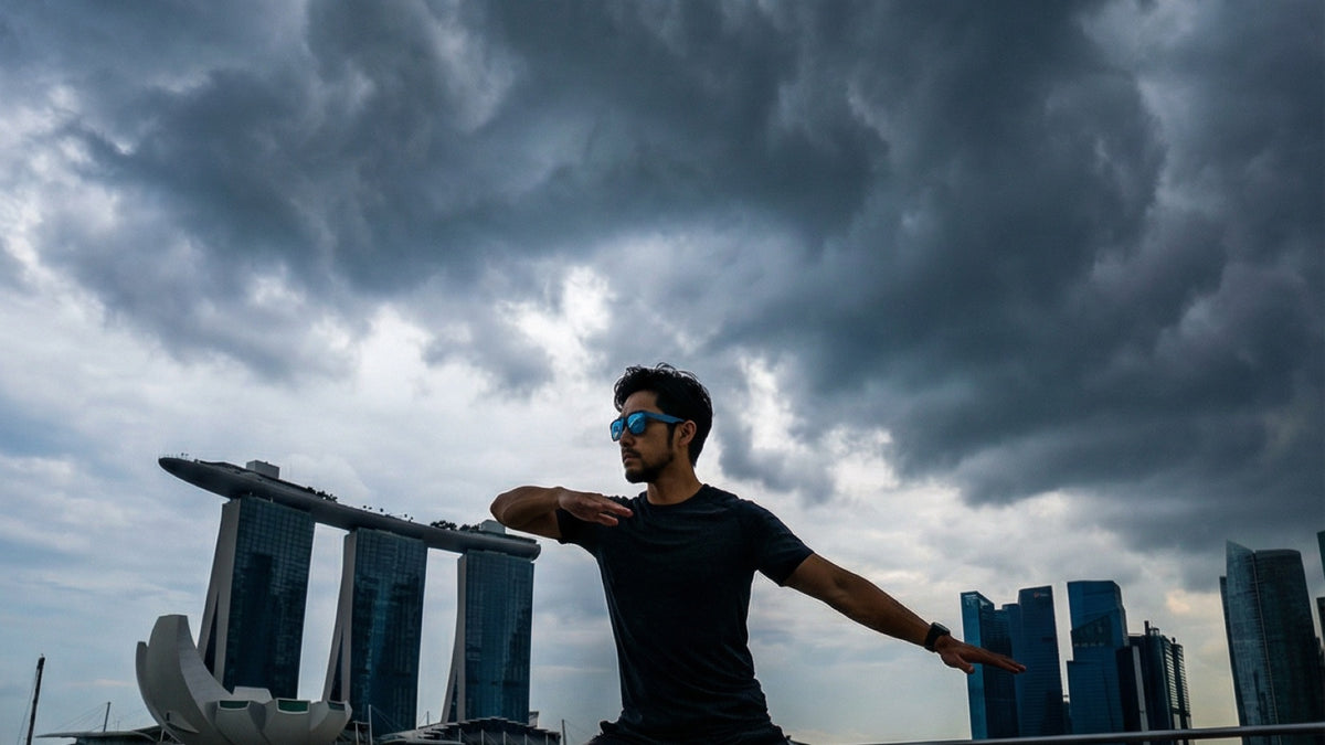 Runner wearing performance sunglasses beside Singapore's waterfront under a cloudy sky