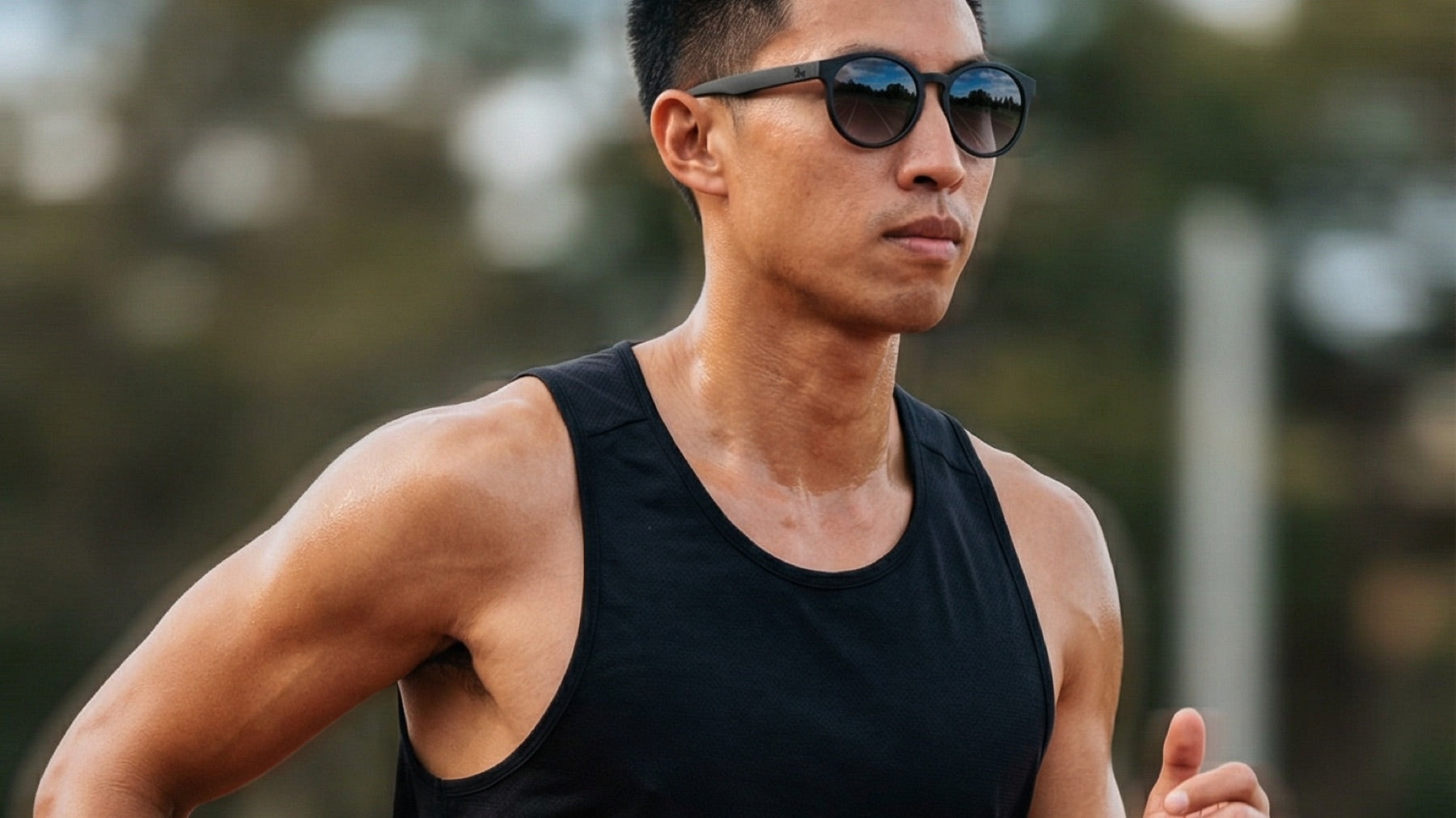 Male runner wearing 2nu sunglasses during an outdoor track run, showing sweat and stable frame fit for Hong Kong running conditions